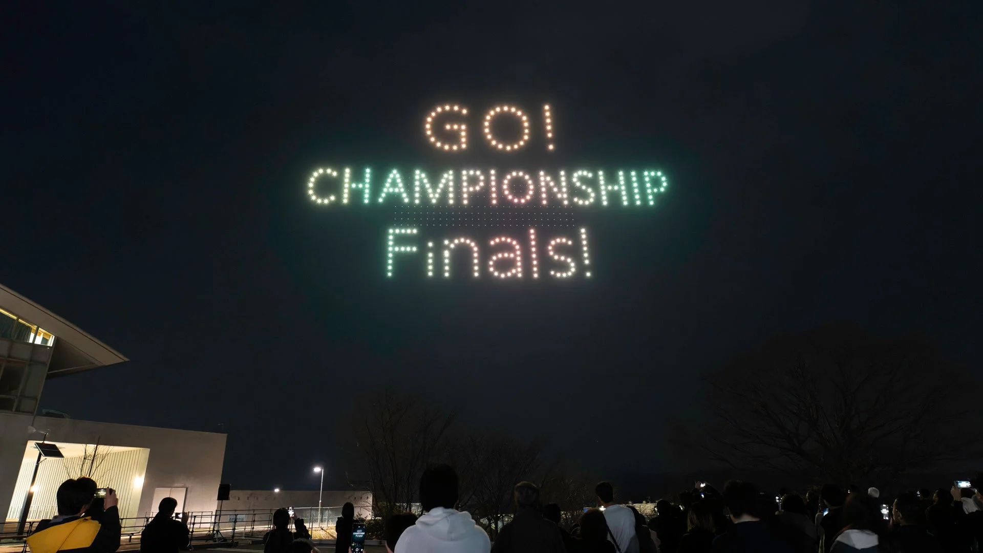 夜空にドローンが「GO! CHAMPIONSHIP Finals!」というメッセージを光で描いています