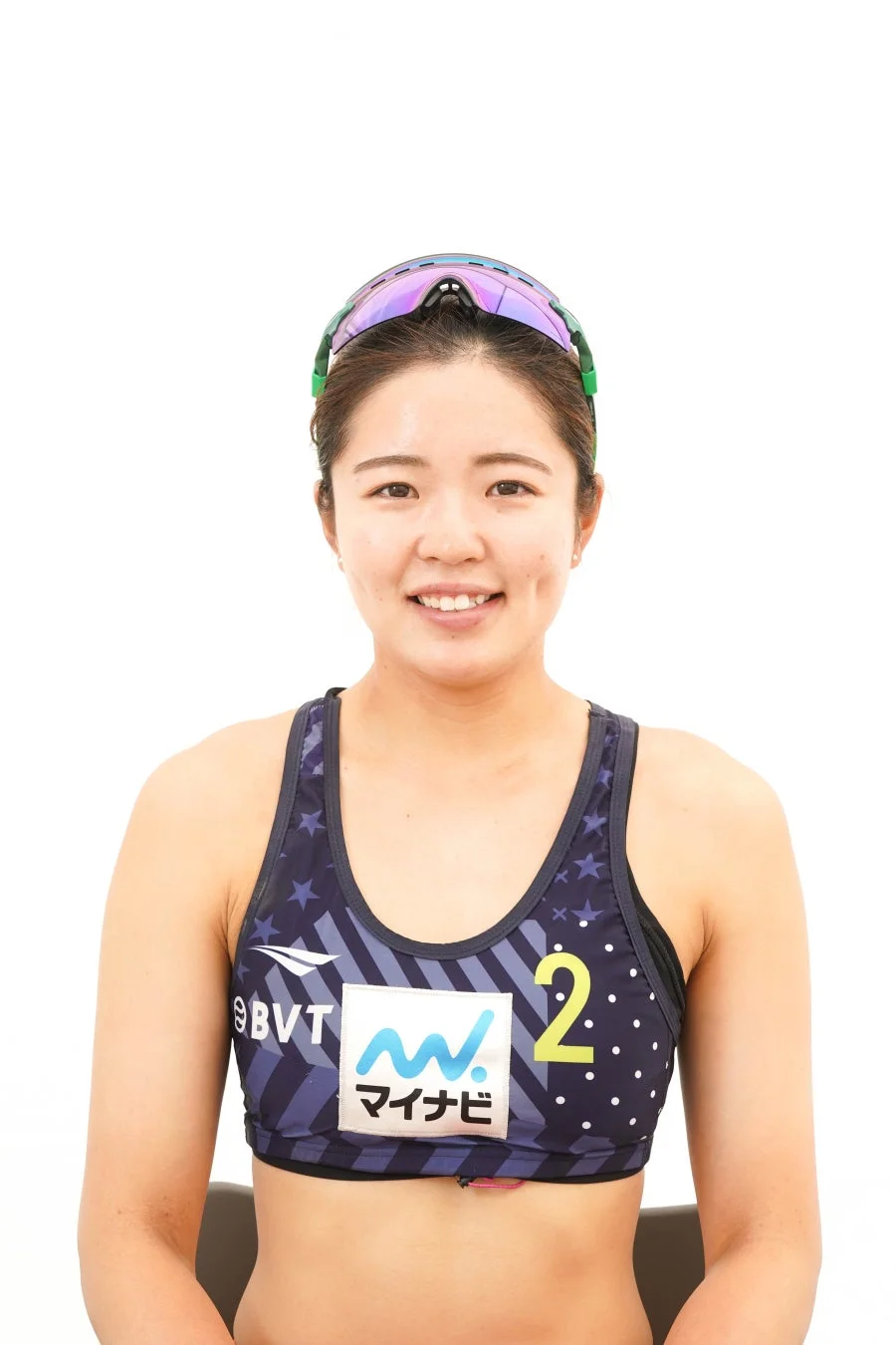 白い背景の前で、笑顔でカメラを見つめる女性アスリートのポートレート