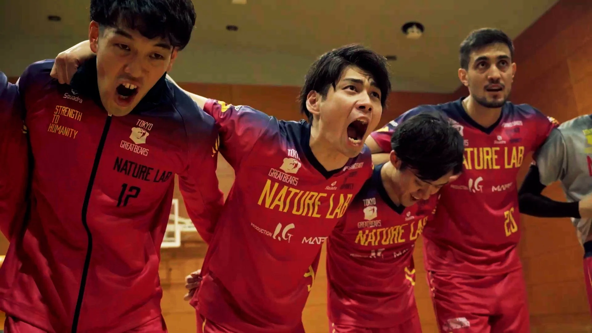 赤いユニフォームを着た男性スポーツ選手たちが、試合中に肩を組み、喜びを爆発させている様子