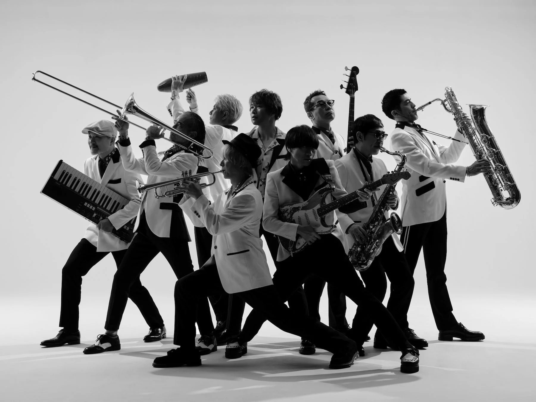 白いスーツを着た複数の男性が様々な楽器を演奏している白黒写真