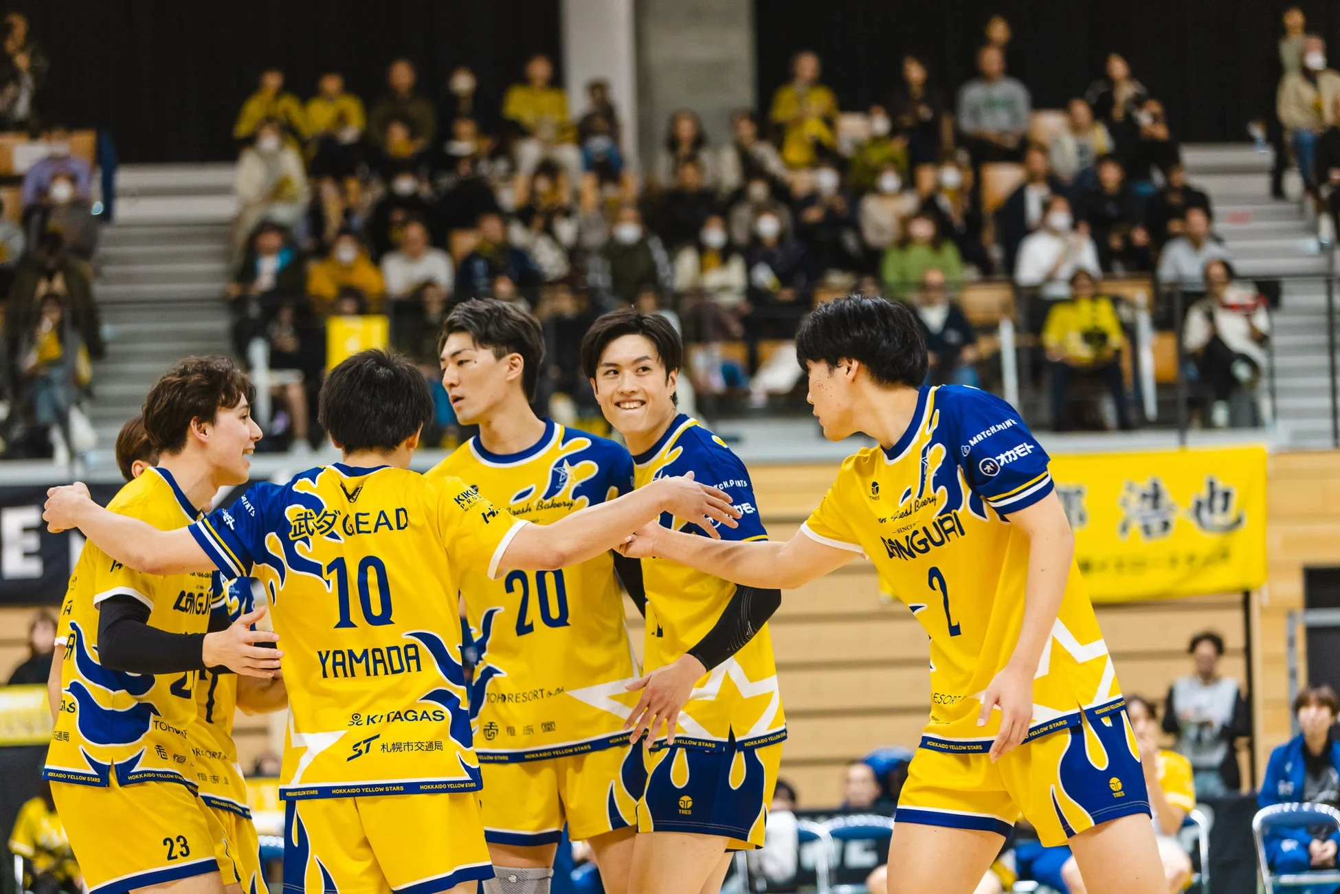 バレーボールの試合中、選手たちがコート上で集まり、互いに声を掛け合っている様子