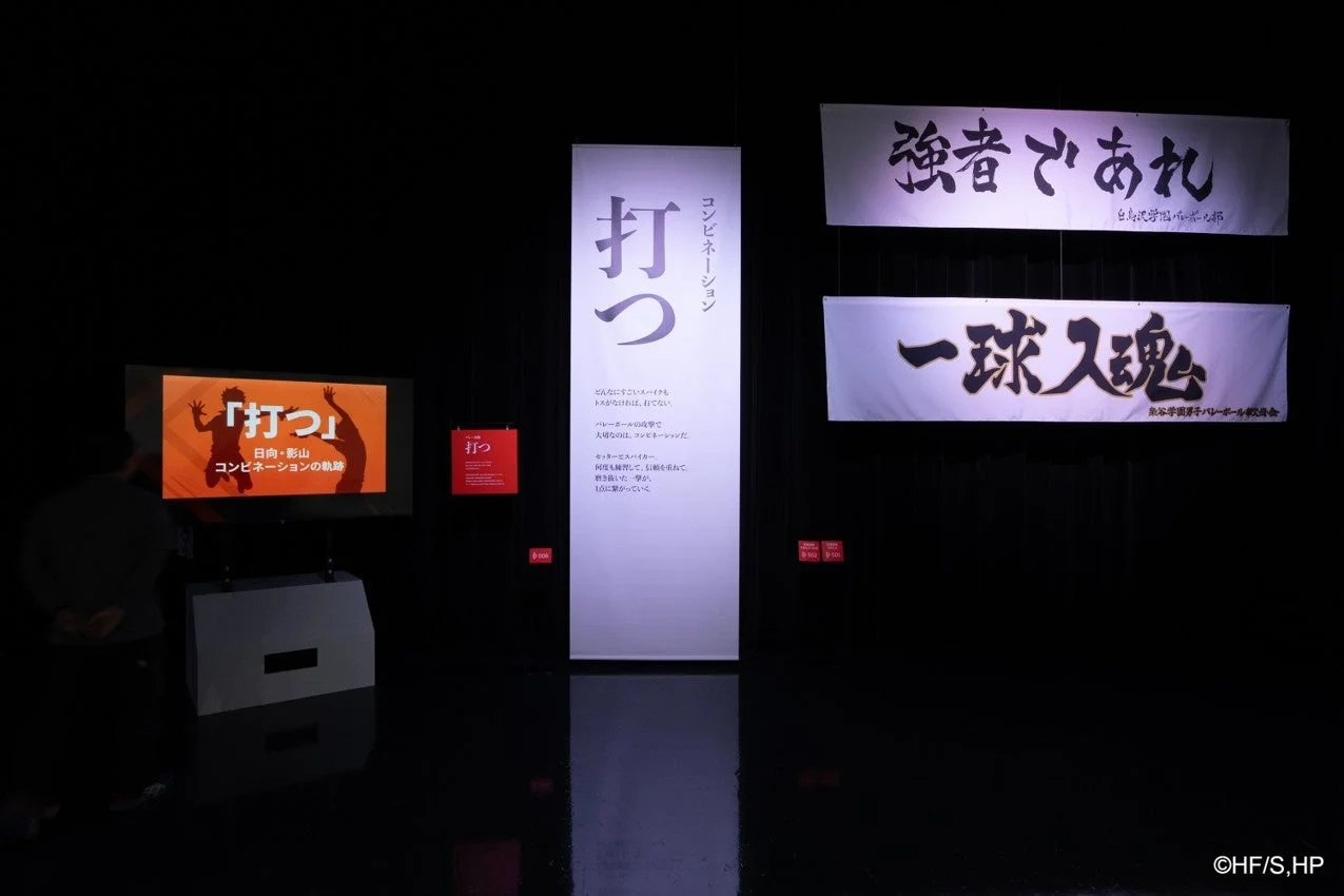 バレーボールの「打つ」と「コンビネーション」をテーマにした展示風景。日向・影山の軌跡に触れ、連携の重要性を説くメッセージや「強者であれ」「一球入魂」といった力強いスローガンが並ぶ。
