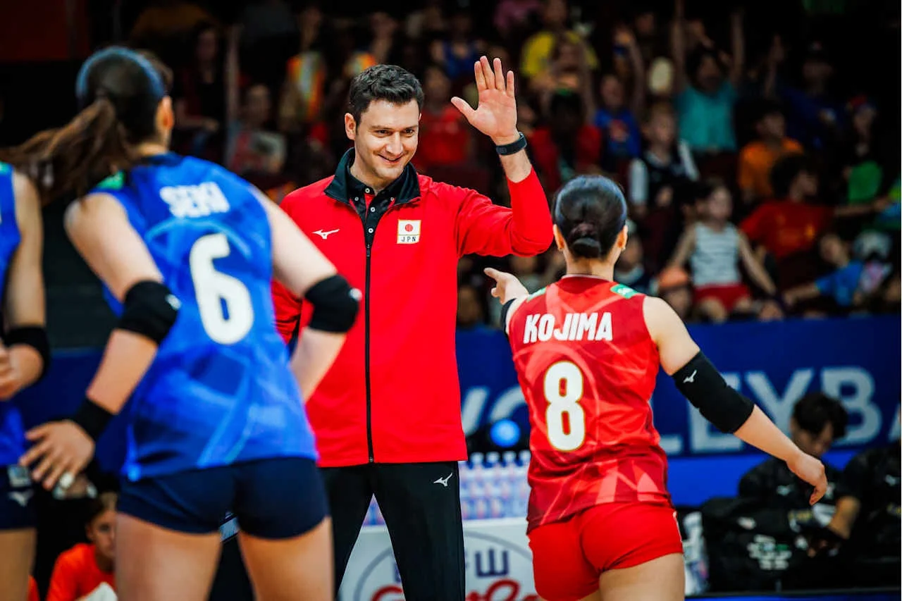 バレーボールの試合中に笑顔で選手とコミュニケーションをとる日本代表コーチ