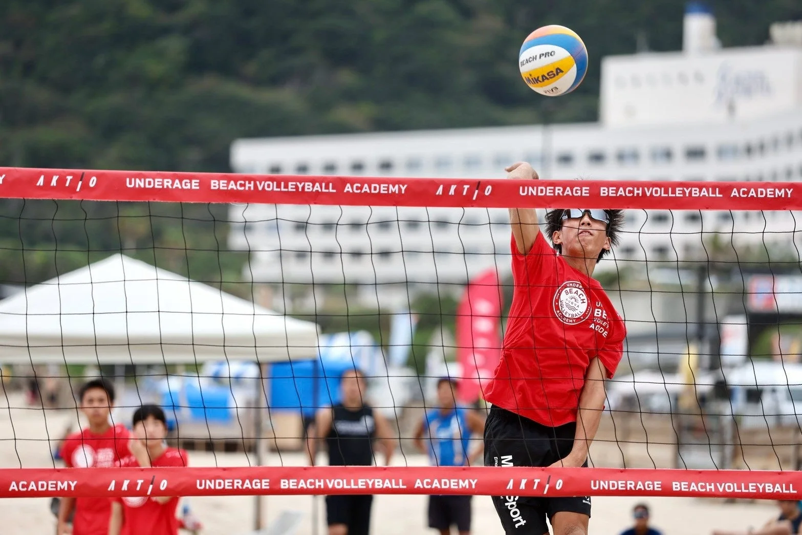 ビーチバレーボールの試合でスパイクを打つ選手